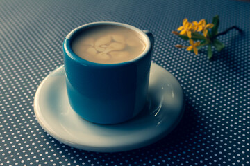 Ceramic mug in light blue and white on a polka dot background. Mug with milk and coffee on neutral background.