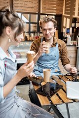 Couple of a young cafe workers have some business conversation while sitting with coffee at the table of their cafe or pastry shop
