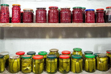 Glass jars with pickles and raspberry jam on the shelves cellar