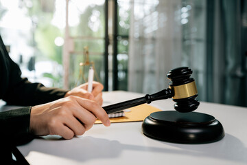 Justice and law concept.Male judge in a courtroom with the gavel, working with, computer and docking keyboard, eyeglasses, on table in morning light