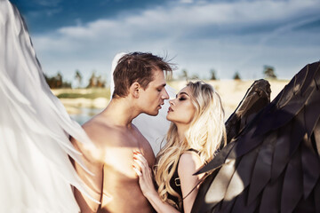 Romantic meeting of angels. Good and evil. A parken and a girl stand by the water at sunset.