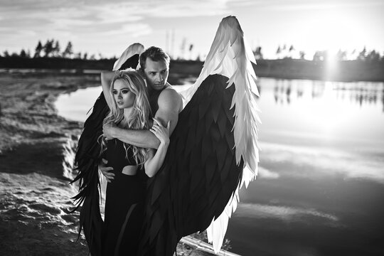 Romantic meeting of angels. Good and evil. A parken and a girl stand by the water at sunset.