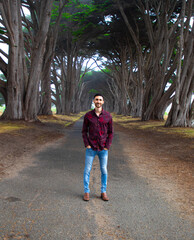 Fototapeta premium Male model dressed up standing in a tree tunnel road