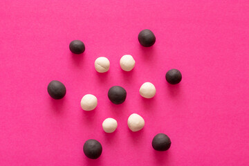 Multiple black and white plasticine balls in layers on pink vibrant background. Concepts of racism