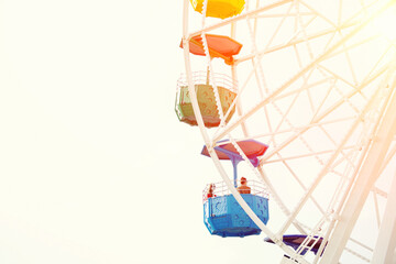 Group of beautiful girls riding on colorful ferris wheel against sunny sky