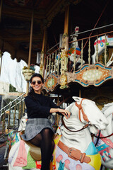 Young attractive woman enjoying time while riding on a merry go round on holidays
