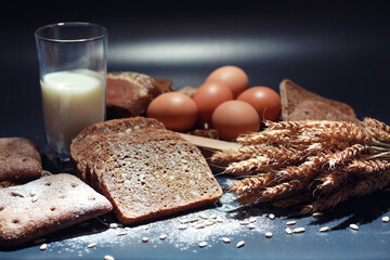 Fresh loaves of bread with wheat and gluten on a black table. Bakery and grocery concept. Fresh, healthy sorts of rye and white loaves food closeup. Fresh homemade bread with cereals.