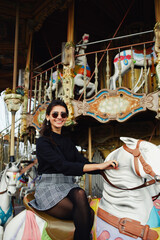 Attractive young woman having fun riding on carousel in amusement park