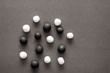 Black and white plasticine balls mixed on a grey background surface. Concepts of unity and...