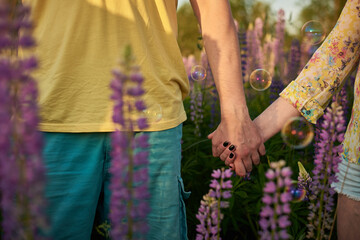
couple holding hands in the middle of a lupine field
