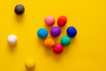 Black, white and yellow balls separated from other colorful balls bunched up in a group. Concepts of race separation, racism and diversity