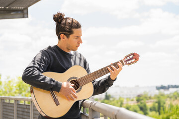 young man playing spanish guitar on the field 