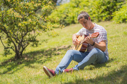 Young Man Playing Spanish Guitar On The Field 