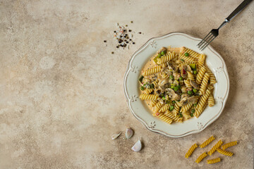 fusilli pasta cooked with peas, champignons and garlic. beige neutral background, top view, copy space