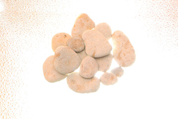 Gray smooth sea stones from the shore on a white background. Backlight below.