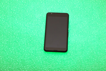 Black smartphone lies on a bright green background. The background is highlighted below.