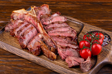 Tender lamb meat, fried medium, served on a board with tomatoes