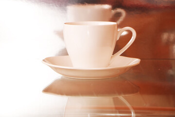 White cup with coffee on a glass table. Background - mirror 3D reflection.