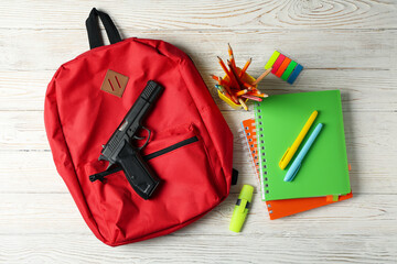 School accessories and gun on white wooden table. School violence