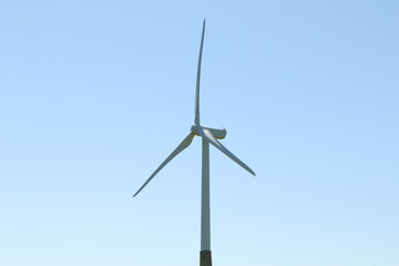 A wind turbine rotates against a blue sky.