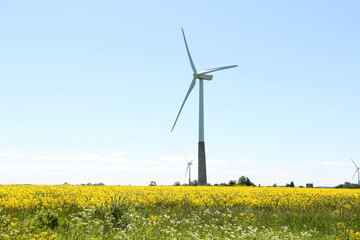 A wind turbine rotates against a blue sky.