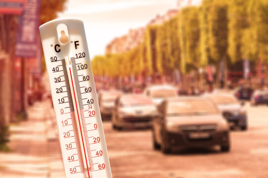 Thermometer in front of cars and traffic during heatwave