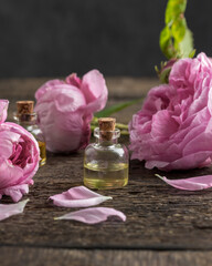 A bottle of rose essential oil with rose de mai flowers