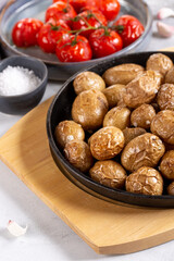 Roasted small whole potatoes in a cast iron skillet on concrete background. Vegetarian or vegan food concept.