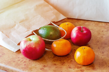 Paper bags, fresh vegetables and fruits on a kitchen table.