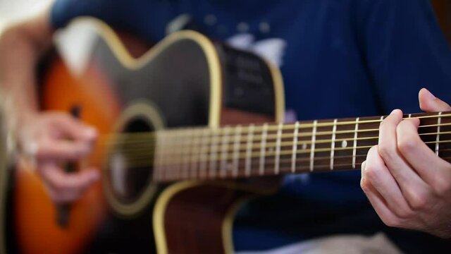 Slow movement on a guy playing acoustic guitar.