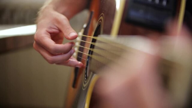 Detail of a guy playing acoustic guitar.