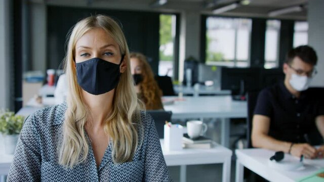 Young people with face masks back at work or school in office after lockdown.