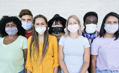 Happy multiracial friends laughing and wearing protective face mask - Group of young peoples having...