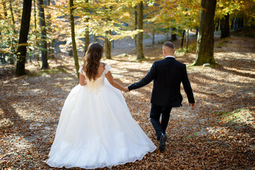 Newlyweds are hugging in the autumn forest.