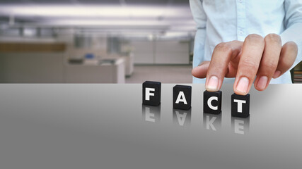 A male person putting cubes labeled with FACT text and FAKE in reflection conceptual image on Social Media Day