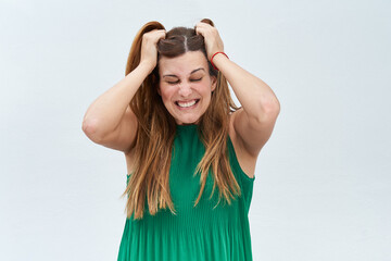 Young woman making the gesture of pulling her hair and stressed on a white background.