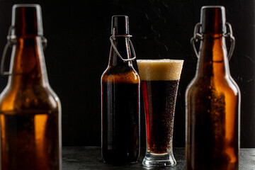 Dark crafted beer in glass and bottle on black background