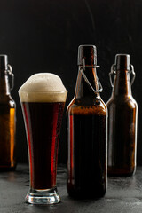 Dark crafted beer in glass and bottle on black background