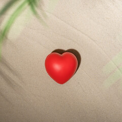 Red heart on sandy tropical beach under branches of palm and shadow palm tree. Valentines day, love. Holiday concept. Creative, background, travel, summer.