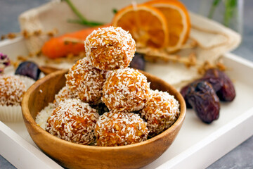 Healthy raw energy balls. Candy vegan balls of dates, coconut pulp, carrots in a wooden bowl are laid out in the shape of a pyramid. Top view, concept of useful home-made candies without sugar