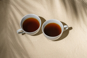 Cup of tea on sand of tropical beach under palm tree branches shadow. Bali, travel