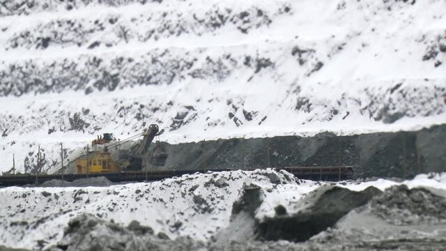 Tilt shift perspective of trucks excavating in quarry. Mining operations.