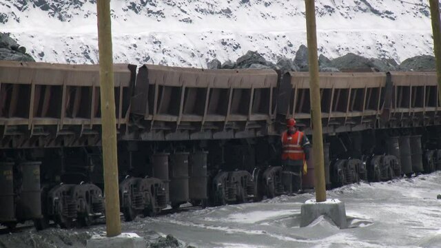 Perspective view of a man walking along the loaded train in mining quarry.