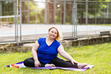 A young positive blonde girl performs an outdoor flexibility exercise. Concept on healthy lifestyle