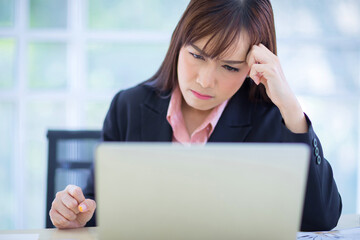 Beautiful Asian women disappointed with the job project. There is a laptop on the table in office....