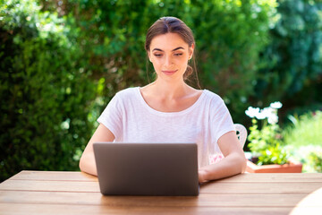 Portrait of attractive young woman using laptop while sitting at desk in the balcony