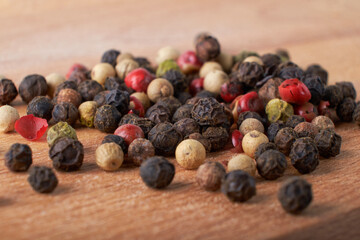 A mixture of peppers. Black, white, red polka dots. Isolated on a wooden background. The selected sharpness