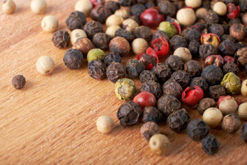 A mixture of peppers. Black, white, red polka dots. Isolated on a wooden background. The selected sharpness