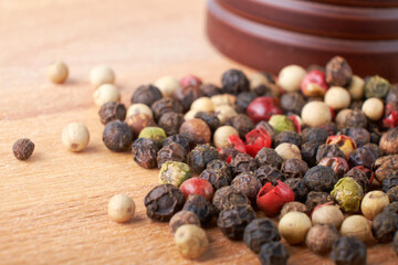 A mixture of peppers. Black, white, red polka dots. Isolated on a wooden background. The selected sharpness