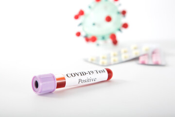 Test tube with a positive COVID-19 test on a white background